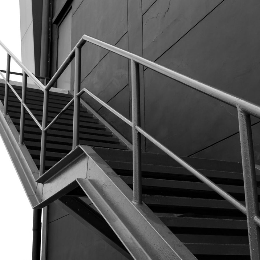 Metal fire escape or emergency exit on Black Wall of Building With Isolated White Background